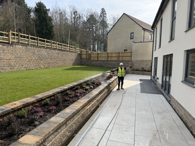 Sam busy watering the flower beds and lawn on Plot 19